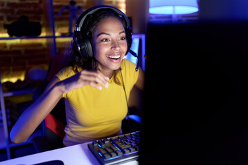 Young african american woman streamer playing video game using computer at gaming room