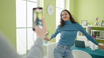 Young beautiful hispanic woman dancing recording online tutorial for social networks at home