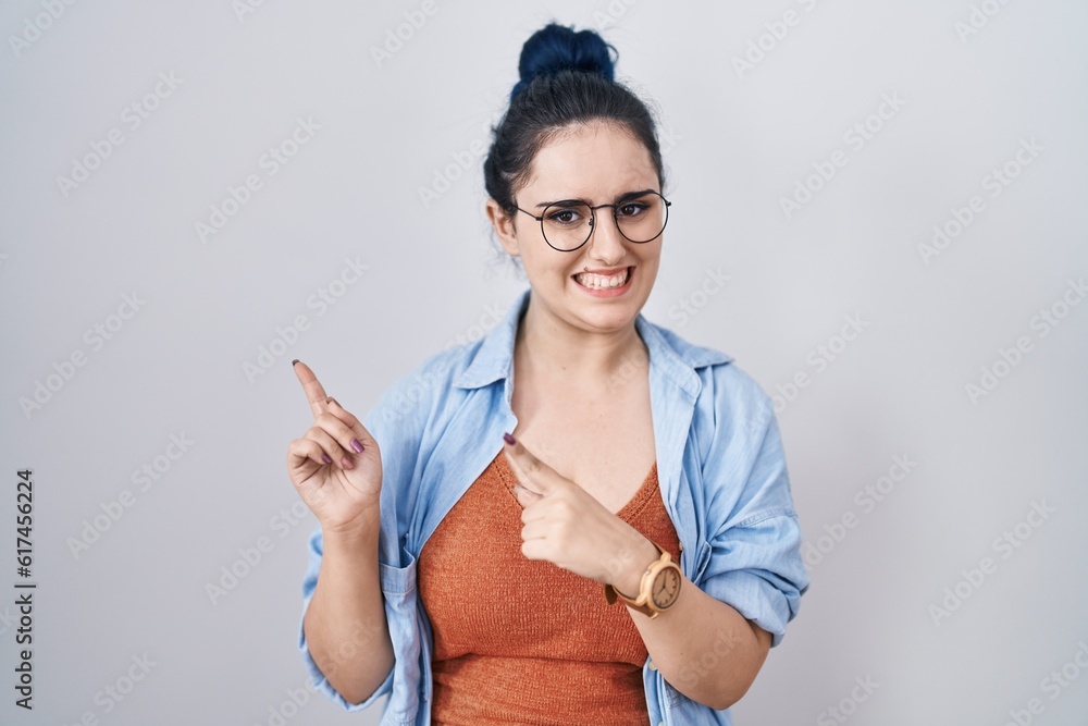 Poster Young modern girl with blue hair standing over white background pointing aside worried and nervous with both hands, concerned and surprised expression