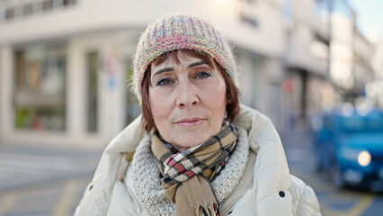 Mature hispanic woman standing with serious expression at street