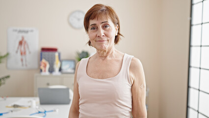 Mature hispanic woman with band aid on arm at clinic