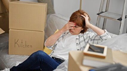 Middle age woman stressed sitting on sofa at new home