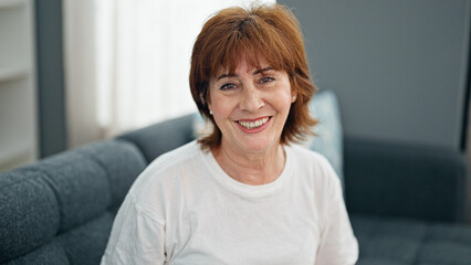 Middle age woman smiling confident sitting on sofa home