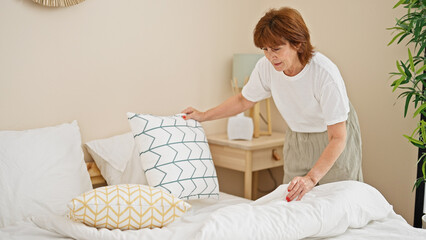 Middle age woman make bed at bedroom