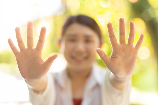 closeup happy woman showing open palm two bare hand 10 fingers. help support giving volunteer people. stop hands on blur green natural background