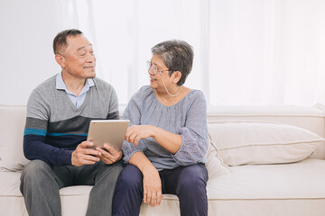 Happy senior couple enjoys technology together at home sofa. Tablet for elderly couples Strengthen family bonds with modern technology.Tech savvy husband and wife benefits of device for seniors.