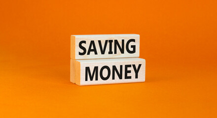 Saving money symbol. Concept words Saving money on wooden blocks on a beautiful orange table orange background. Business, support and saving money concept. Copy space.