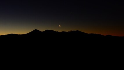 la luna menguante aparece sobre las montañas