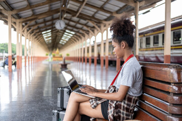 Young woman girl female sitting use computer laptop and travel bag suit case on the floor at station