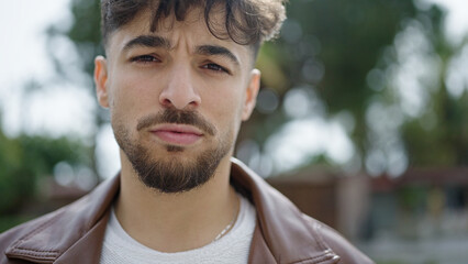 Young arab man standing with serious expression at park