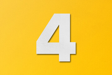 White paper type paper alphabet number 4 isolated on yellow background.