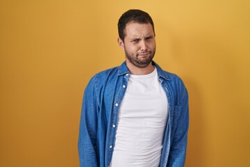 Hispanic man standing over yellow background skeptic and nervous, frowning upset because of problem. negative person.