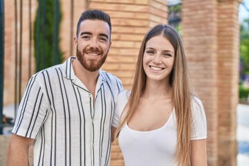 Fototapeta premium Man and woman couple smiling confident hugging each other at street