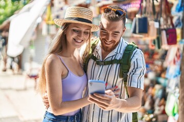 Man and woman tourist couple smiling confident using smartphone at street market