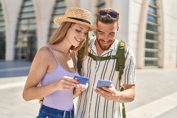 Man and woman tourist couple using smartphone and credit card at street