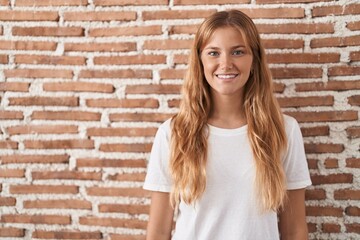 Young caucasian woman standing over bricks wall with a happy and cool smile on face. lucky person.