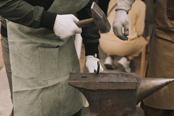 The blacksmith forging the metal on the anvil in smithy