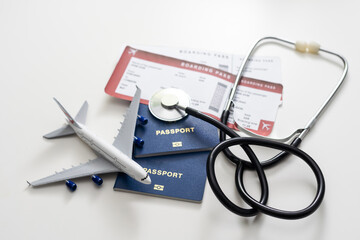 Medical Tourism, medical travel concept. Stethoscope, toy plane and passport on grey background.