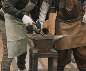 The blacksmith forging the metal on the anvil in smithy