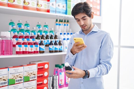 Young hispanic man customer make photo by smartphone to medicine bottle at pharmacy