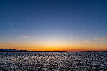 A colorful and fiery sunset against a backdrop of mountains and ocean