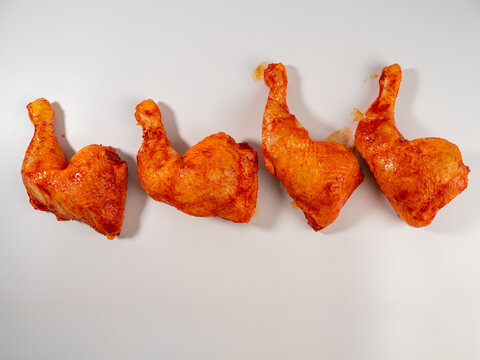 Marinated chicken drumstick or legs on a white plate. Marinated chicken leg close-up.