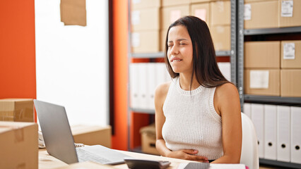 Young beautiful hispanic woman ecommerce business worker suffering for hungry working at office