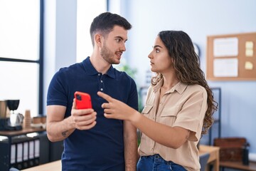 Young hispanic couple business workers using smartphone working at office