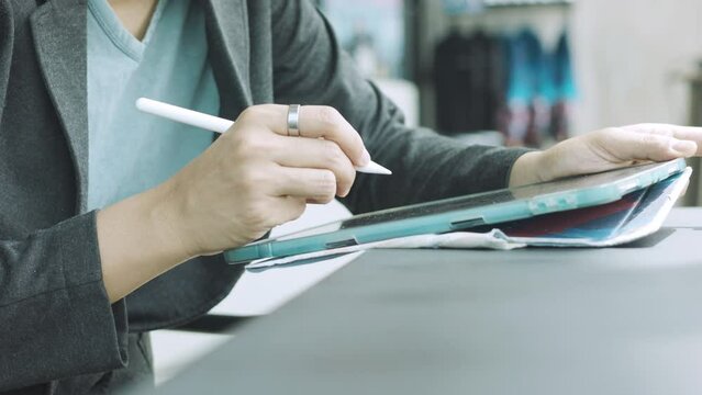 Hands with stylus tablet of Asian woman embraces the modern lifestyle. Witness the authentic connection she creates through the social network, leveraging wireless technology to excel as an executive.