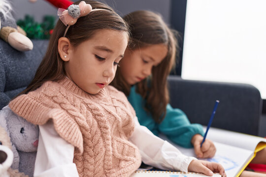 Adorable girls drawing on notebook celebrating christmas at home