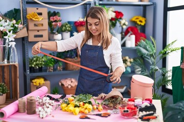 Young woman florist smiling confident prepare bouquet of flowers at florist