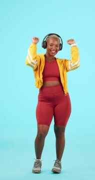 Fitness, black woman dance and with headphones against a blue background for health wellness. Music or training, motivation or positive and happy African female person dancing for happiness.