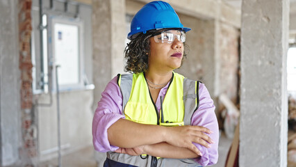Young beautiful latin woman builder standing with serious face and arms crossed gesture at...