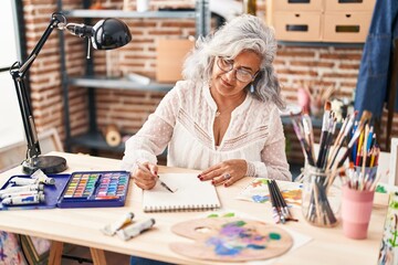 Middle age woman artist drawing on notebook at art studio