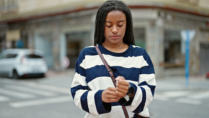 African american woman wearing watch waiting with serious expression at street