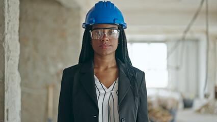 African american woman architect standing with relaxed expression at construction site