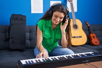 Young hispanic woman musician playing piano keyboard at music studio © Krakenimages.com
