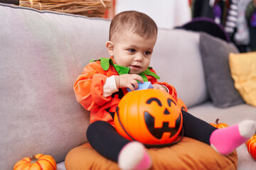 Adorable hispanic baby having halloween party wearing pumpkin costume at home