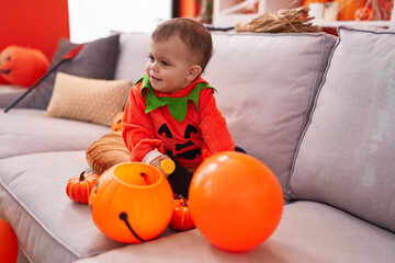 Adorable hispanic baby having halloween party wearing pumpkin costume at home