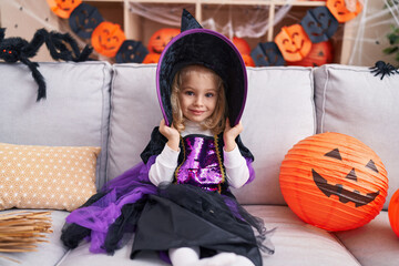 Adorable blonde girl wearing witch costume having halloween party at home