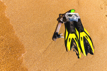 Snorkeling mask with flippers on a sandy beach. Yellow flippers on the shore. Beach vacation, snorkeling equipment on sand texture background. Diving and snorkelling