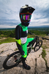 Wide angle view of a young man cycling down a hill with a blue sky in the background. A cyclist in...