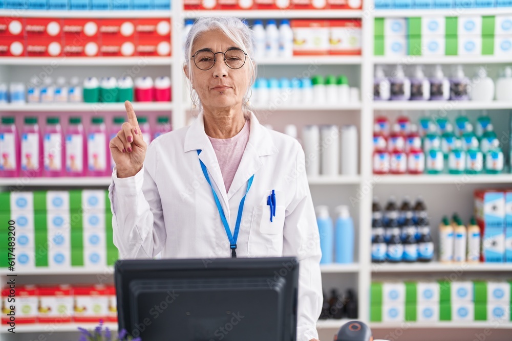 Sticker middle age woman with tattoos working at pharmacy drugstore showing and pointing up with finger numb