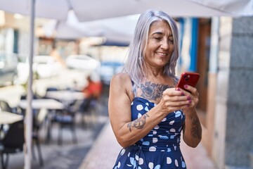 Middle age grey-haired woman smiling confident using smartphone at street