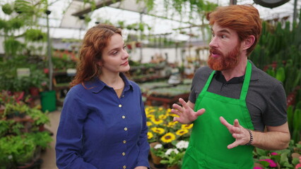 Male Florist at Flower Shop wearing Green Apron helping Female Customer in Local Business Store