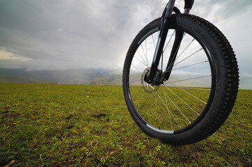 Detail of a mountain bike wheel close-up on a field in the mountains on a cloudy foggy day during a workout