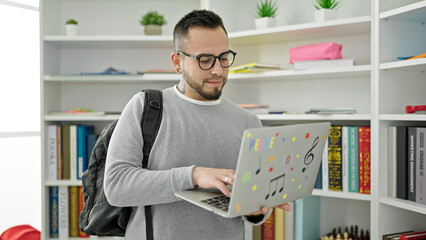 Hispanic man student using laptop at library university