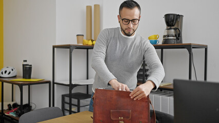 Hispanic man business worker putting laptop in briefcase at office