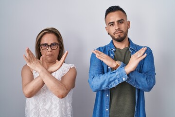 Hispanic mother and son standing together rejection expression crossing arms doing negative sign, angry face