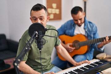 Two men musicians singing song playing piano and classical guitar at music studio